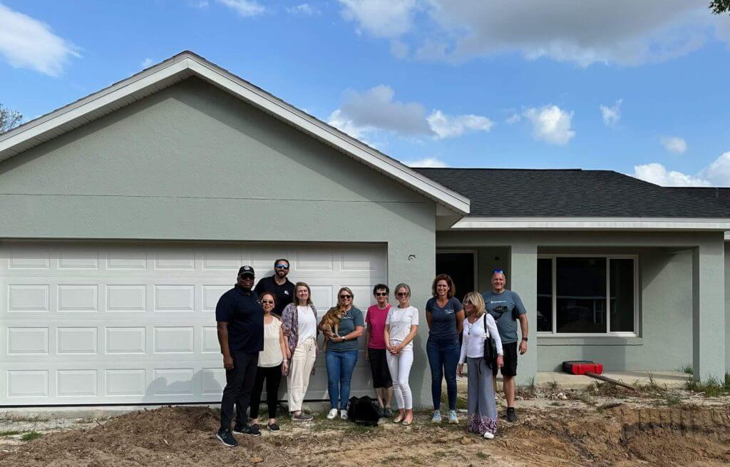 Grant Anderson at RealWealth and a group of investors standing in front of a turnkey rental property.  
