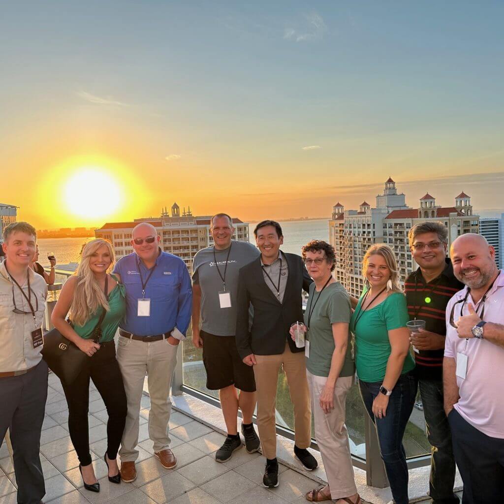 RealWealth's Grant and Rebekah Anderson with a group of real estate investors, smiling on a rooftop at sunset.