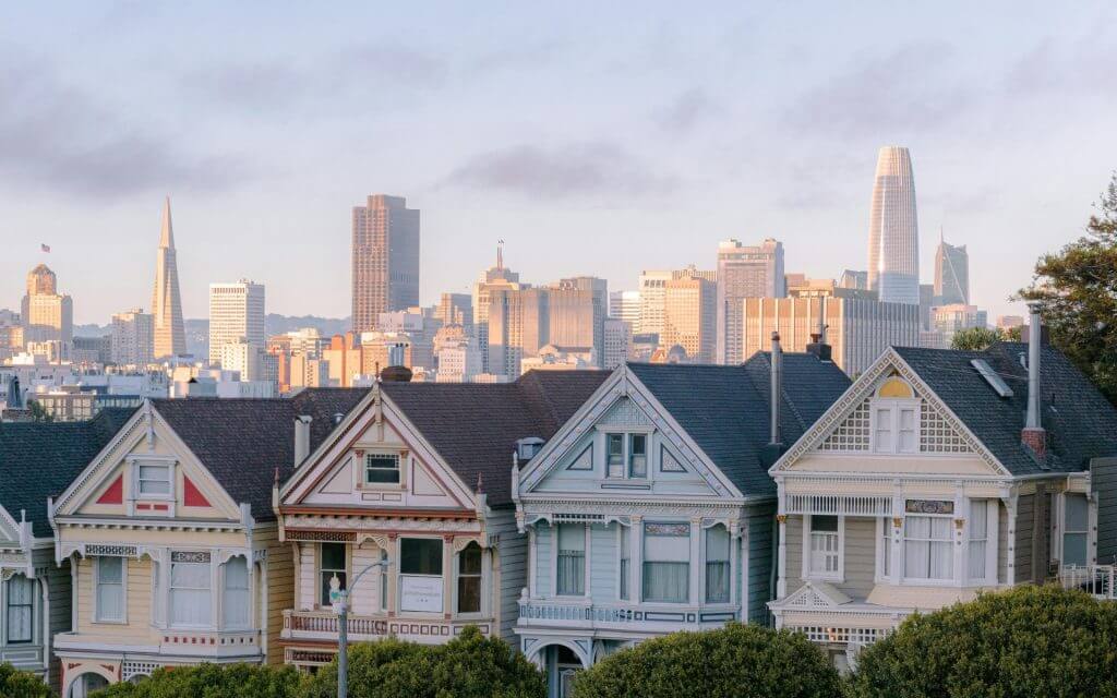 Victorian Painted Ladies and San Francisco skyline during sunrise.